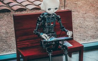 Picture of robot sat on red park bench, working on laptop. Mortgage Broers & AI - blog by Martland Mortgages in Southport, Merseyside.